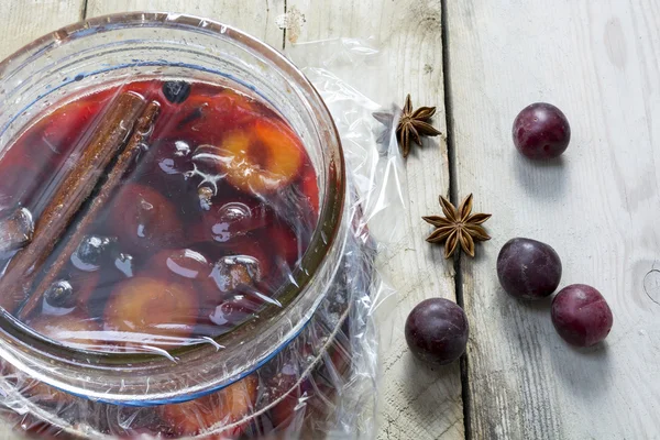 Homemade pickled plums  in a glass jar on rustic wood — Stock Photo, Image
