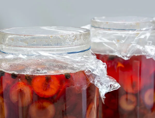 Preserved red fruits with spices into two glass jars — Stock Photo, Image