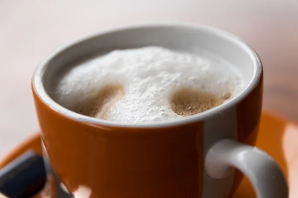 Taza de café naranja con capuchino y espuma de leche — Foto de Stock