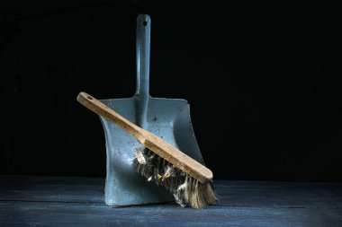 Ahşap saplı eski el fırçası ve eskimiş metal bir faraşın üzerine yaslanmış bir sürü kir. Eskimiş temizlik araçları, kopyalama alanı.