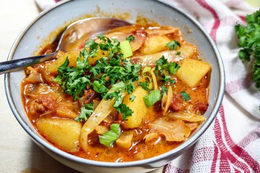 Lahana, patates, sucuklu sosis ve domatesli maydanozlu güveç, sonbahar veya kış vakti sıcak yemek, seçilmiş odak, dar tarla derinliği