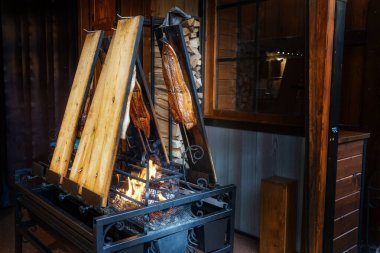 Somon, şöminenin üzerinde tahta kalaslarla birlikte bir rafta tütsülenir. Lubeck, Kuzey Almanya 'da bir Noel pazarı lezzeti. Karanlık arka plan, kopya alanı, seçilmiş odak alanı, dar alan derinliği.