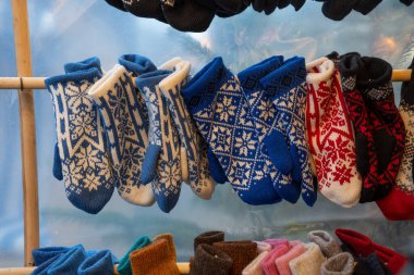 Kış desenli yün eldivenler Noel pazarında bir tezgahta asılı duruyor, el yapımı ürünlerle mevsimlik iş, seçilmiş odak, dar alan derinliği