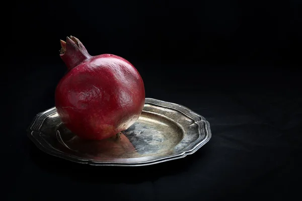 Granátové jablko na stříbrný talíř, tmavé pozadí — Stock fotografie