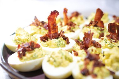 Yumurta yarımları yumurta sarısı, hardal ve ottan yapılmış ve çıtır çıtır pastırmayla süslenmiş ev yapımı parti atıştırmalıkları, kopyalama alanı, seçilmiş odak alanı, dar alan derinliği.