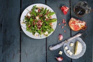 roka, beyaz peynir ve rustik ahşap üzerine nar salatası