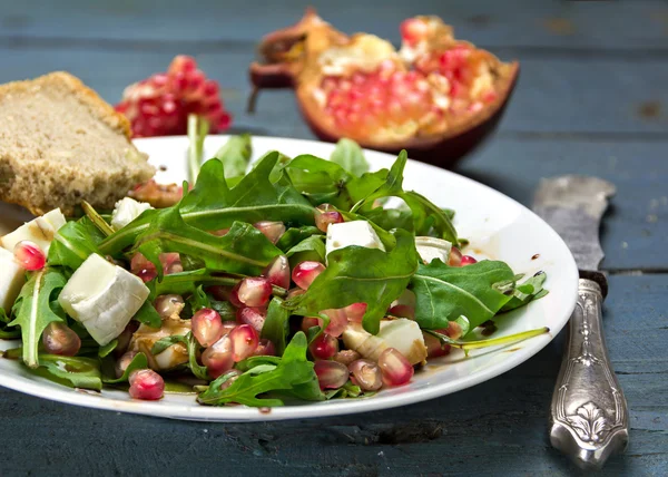 Rocket salad with  feta cheese and pomegranate on an rustic wood — Stock Photo, Image