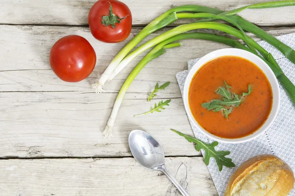 Soupe de tomates avec pain, oignons verts et roquette garnissent sur lumineux — Photo