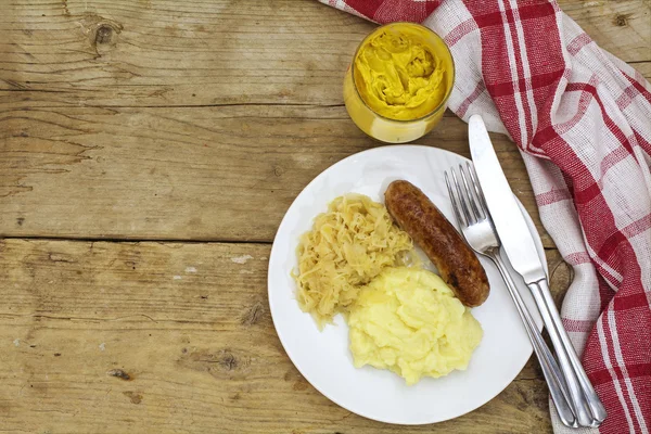 Bratwurst com purê de batata de chucrute e mostarda em um rusti — Fotografia de Stock