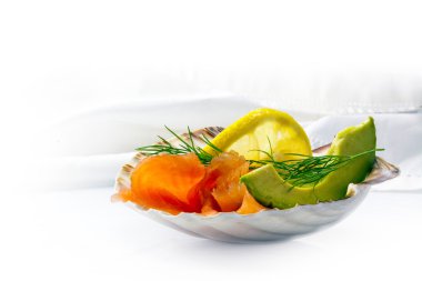 Smoked salmon with avocado, lemon and dill in a scallop shell is clipart