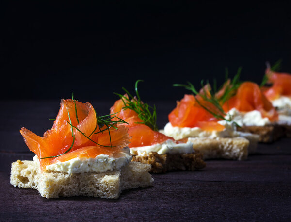 Row of festive canapes in star shape with smoked salmon on dark