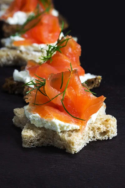 Sternenförmige Canapes mit Räucherlachs auf dunkelbraunem Holz, — Stockfoto