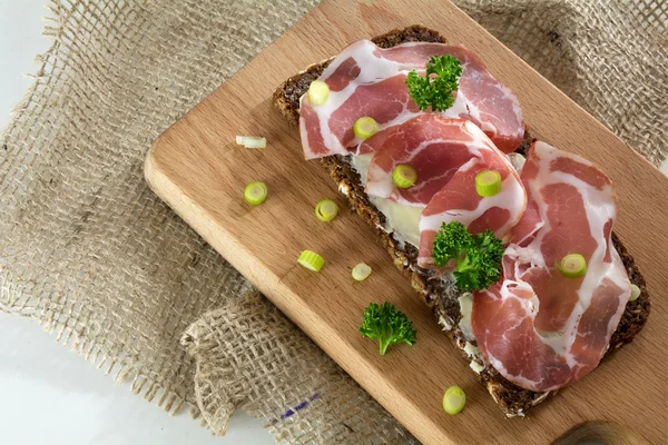 İtalyan jambon coppa ya da capicola bir ahşap kesim üzerinde karanlık ekmek üzerinde — Stok fotoğraf