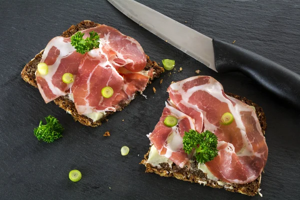 Dark bread with Italian coppa or capicola ham on a dark slate pl — Stock Photo, Image