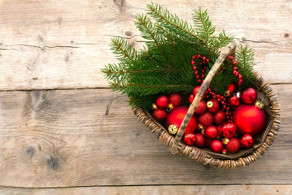 Basket with red christmas baubles and pine branches from above o — Stock Photo, Image