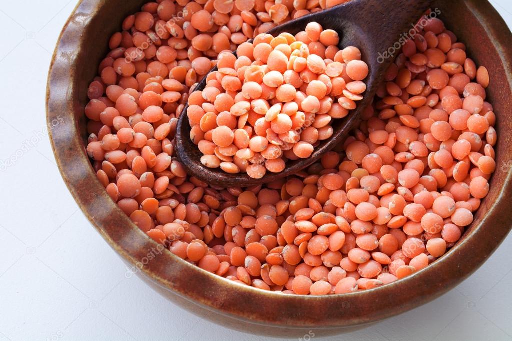 Red lentils in a bowl with a wooden spoon