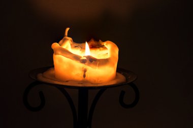 Beyaz Mum alevi ve bir demir şamdan üzerinde eriyen mum ile