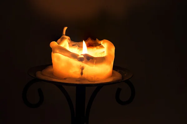 White candle with flame and melting wax on an iron candlestick — Stock Photo, Image