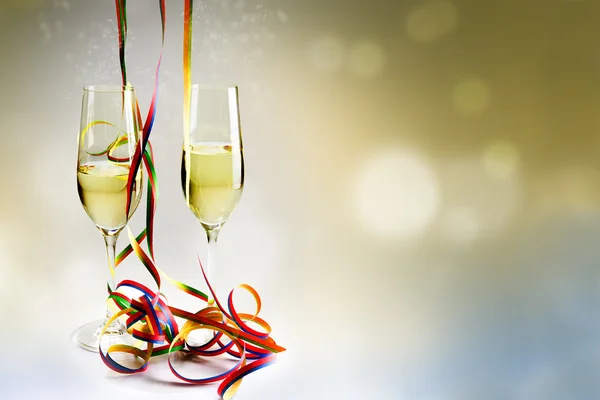 Flöjter champagne glas och färgglada streamers mot en bokeh — Stockfoto