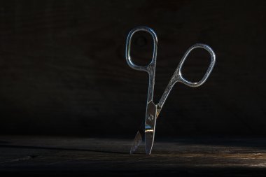 standing nail scissors with some rust against a dark rustic wood clipart