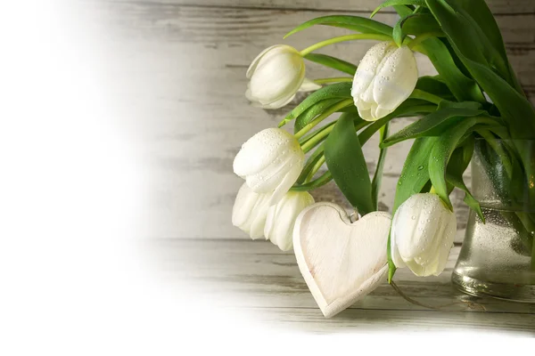 Белые тюльпаны и деревянное сердце формы против серого дерева, угол — стоковое фото