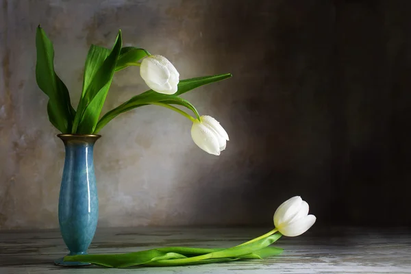 Bílé tulipány a modrá porcelánová váza na staré dřevěné tabulce ag — Stock fotografie