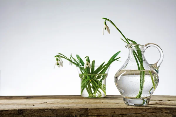 Kardelen çiçek bir brigh karşı rustik ahşap üzerine cam vazo içinde — Stok fotoğraf