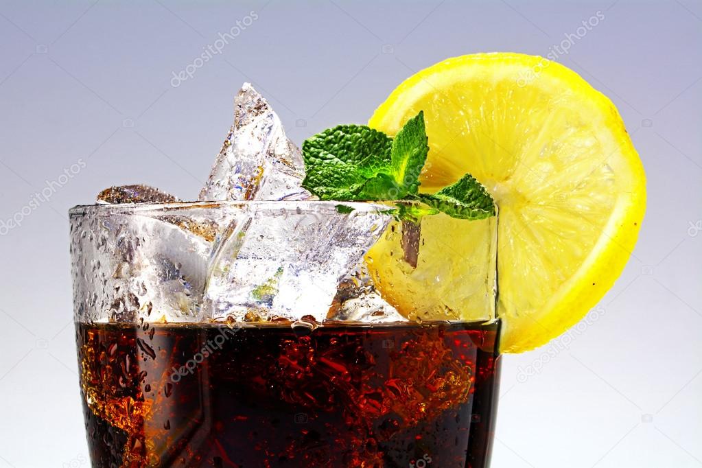 top of a glass of cola or coke with ice cubes, lemon slice and p