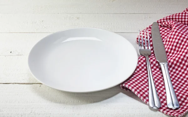 Empty plate with cutlery and red white napkin on a white rustic — Stock fotografie