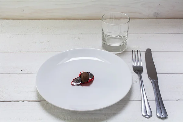 Plato blanco con un pequeño huevo de Pascua de chocolate en papel de aluminio rojo abierto , — Foto de Stock