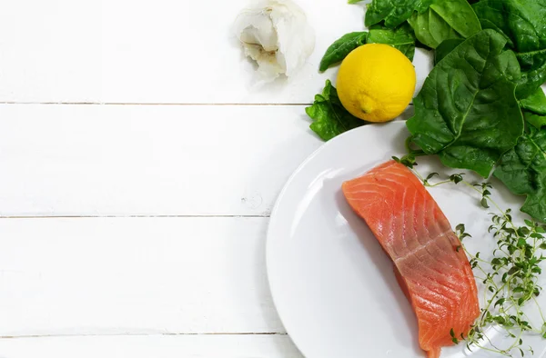 Raw salmon fillet with aromatic herbs, garlic, lemon and spinach — Stock Photo, Image