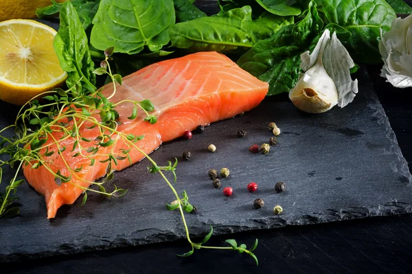 Raw salmon fillet with thyme, garlic, lemon and spices on a dark — Stockfoto