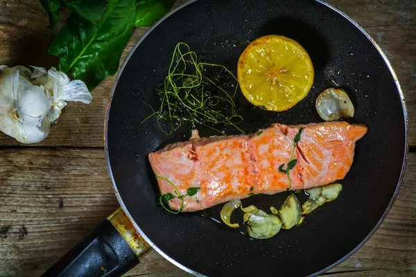 Filete de salmón freír en la sartén con hierbas aromáticas, ajo y — Foto de Stock