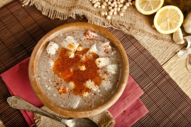 Turkish traditional tripe soup on rustic background with wooden table clipart
