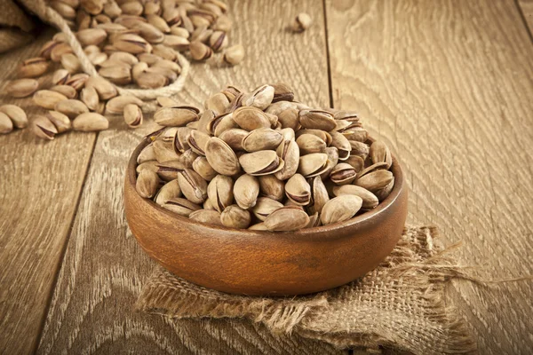 Pistacchi in un piatto di legno e concetto di sfondo. Focus selettivo — Foto Stock