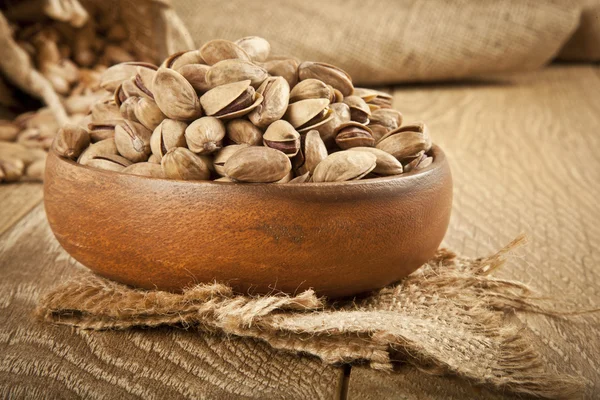 Pistacchi in un piatto di legno e concetto di sfondo. Focus selettivo — Foto Stock