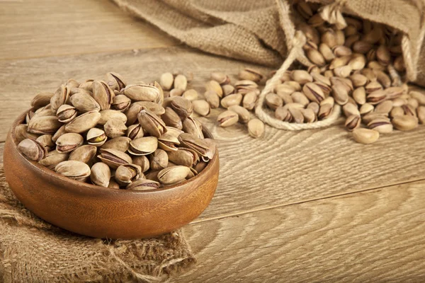 Pistachios in a wooden plate and concept background. Selective focus — Stock Photo, Image