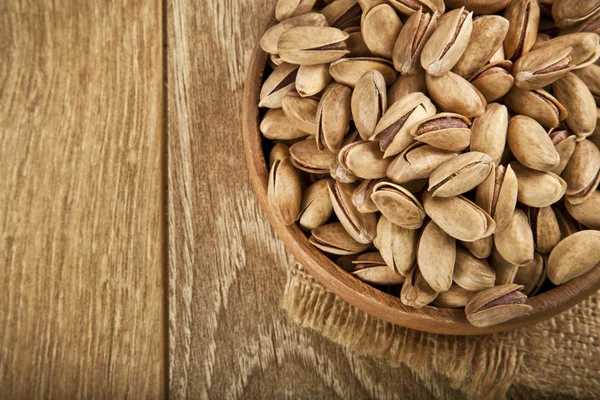 Pistacchi in un piatto di legno e concetto di sfondo. Focus selettivo — Foto Stock