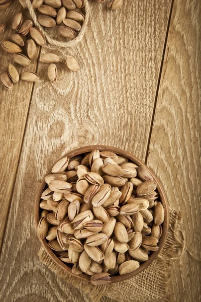 Pimpernoten (pistaches) in een houten plaat en concept achtergrond. Selectieve aandacht — Stockfoto
