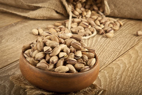 Pistacchi in un piatto di legno e concetto di sfondo. Focus selettivo — Foto Stock