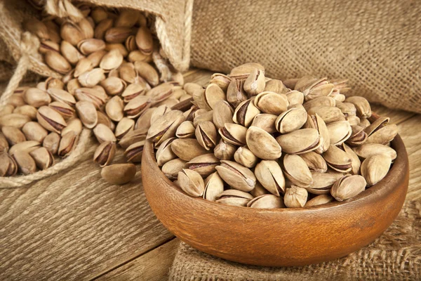 Pistachios in a wooden plate and concept background. Selective focus — Stock Photo, Image