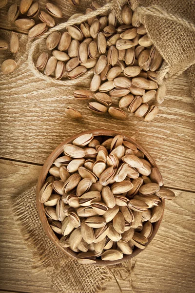 Pistacchi in un piatto di legno e concetto di sfondo. Focus selettivo — Foto Stock