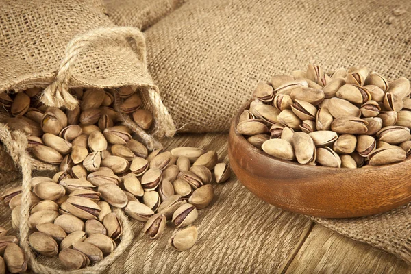 Pistachios in a wooden plate and concept background. Selective focus — Stock Photo, Image