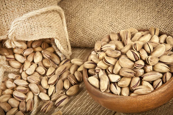 Pistachios in a wooden plate and concept background. Selective focus — Stock Photo, Image