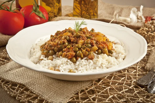 Pilaf de riz turc traditionnel avec viande et légumes pois dans une assiette blanche sur fond de concept en bois — Photo