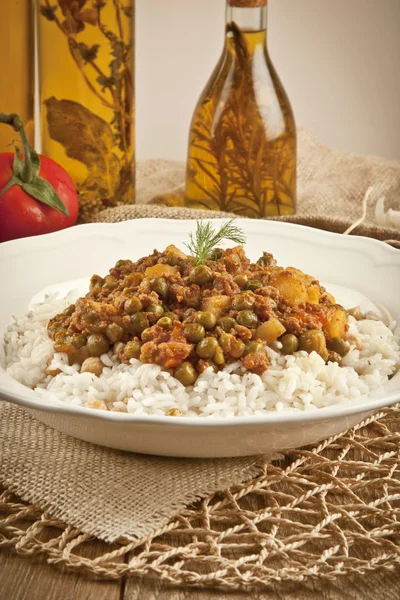 Pilaf de arroz turco tradicional con guisante de carne y verduras en plato blanco sobre fondo concepto de madera — Foto de Stock