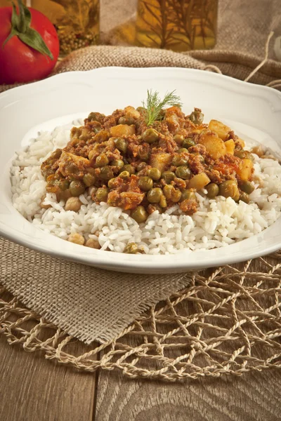 Pilaf de riz turc traditionnel avec viande et légumes pois dans une assiette blanche sur fond de concept en bois — Photo