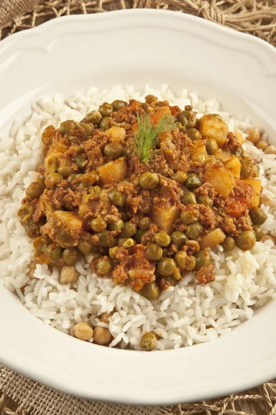 Pilaf de riz turc traditionnel avec viande et légumes pois dans une assiette blanche sur fond de concept en bois — Photo