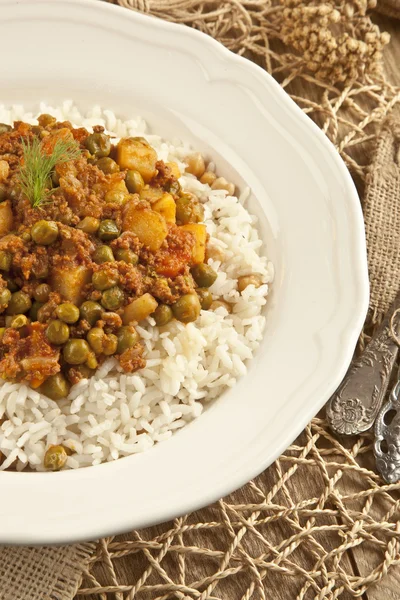 Pilaf de riz turc traditionnel avec viande et légumes pois dans une assiette blanche sur fond de concept en bois — Photo