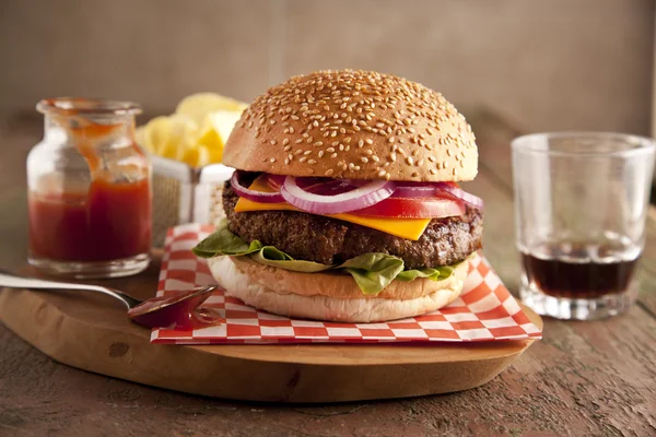 Cheeseburger deluxe clássico com alface, cebola, tomate e picles em um pão de sementes de gergelim — Fotografia de Stock